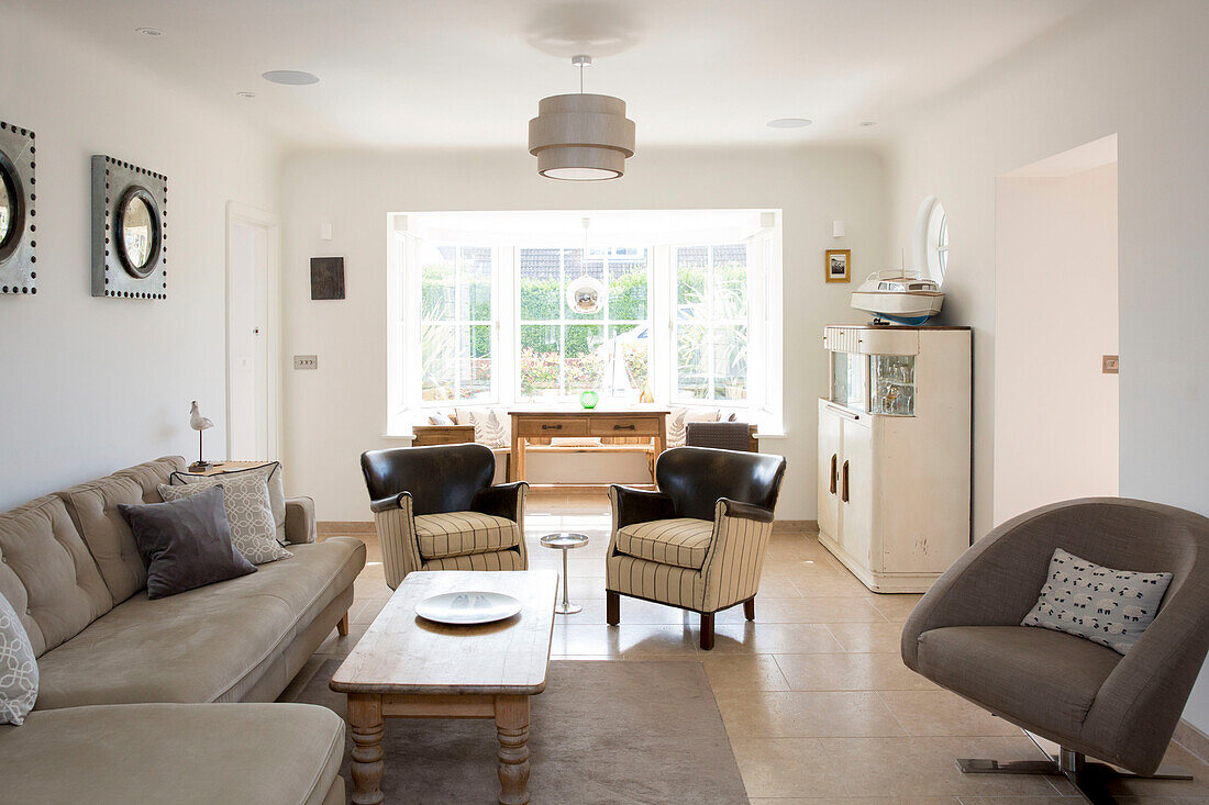 Paar gepolsterte Stühle mit Sofa und Schrank in einem Haus in West Wittering, West Sussex, England