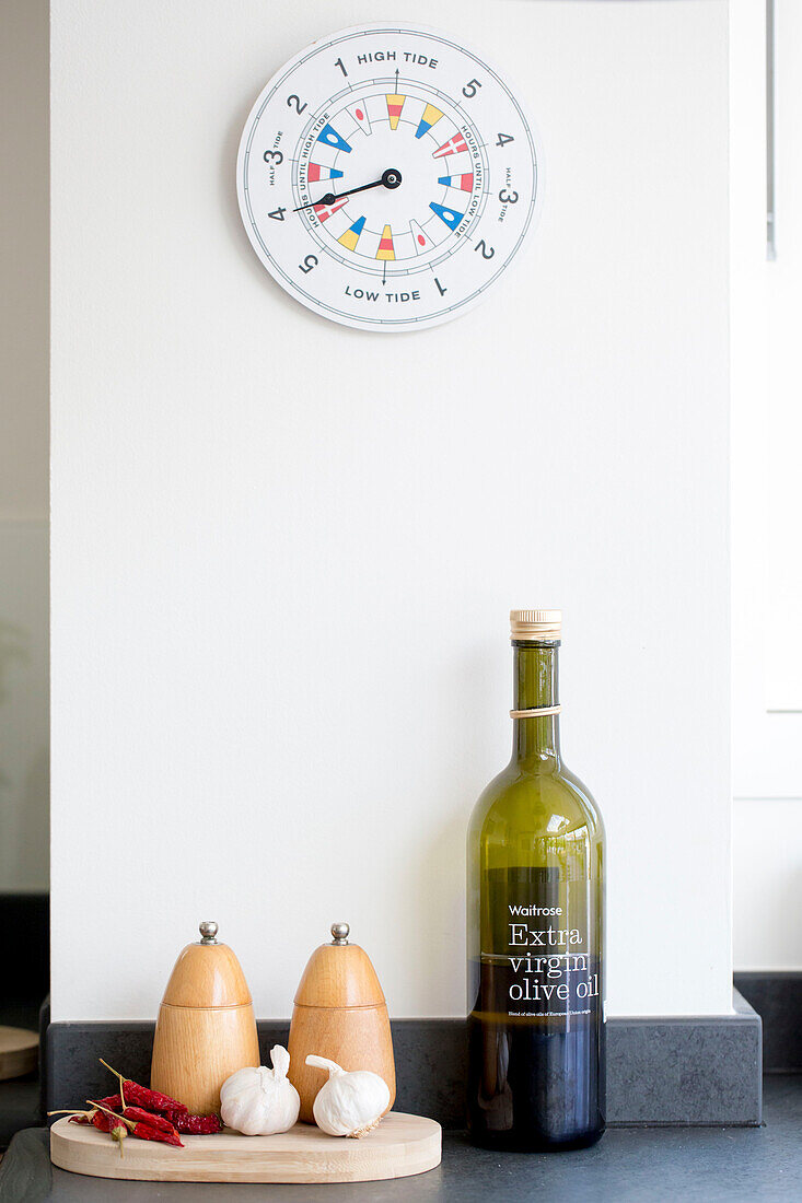 Gezeitenuhr in der Küche über Salz und Pfeffer mit Olivenöl in einem Haus in West Wittering, West Sussex, England
