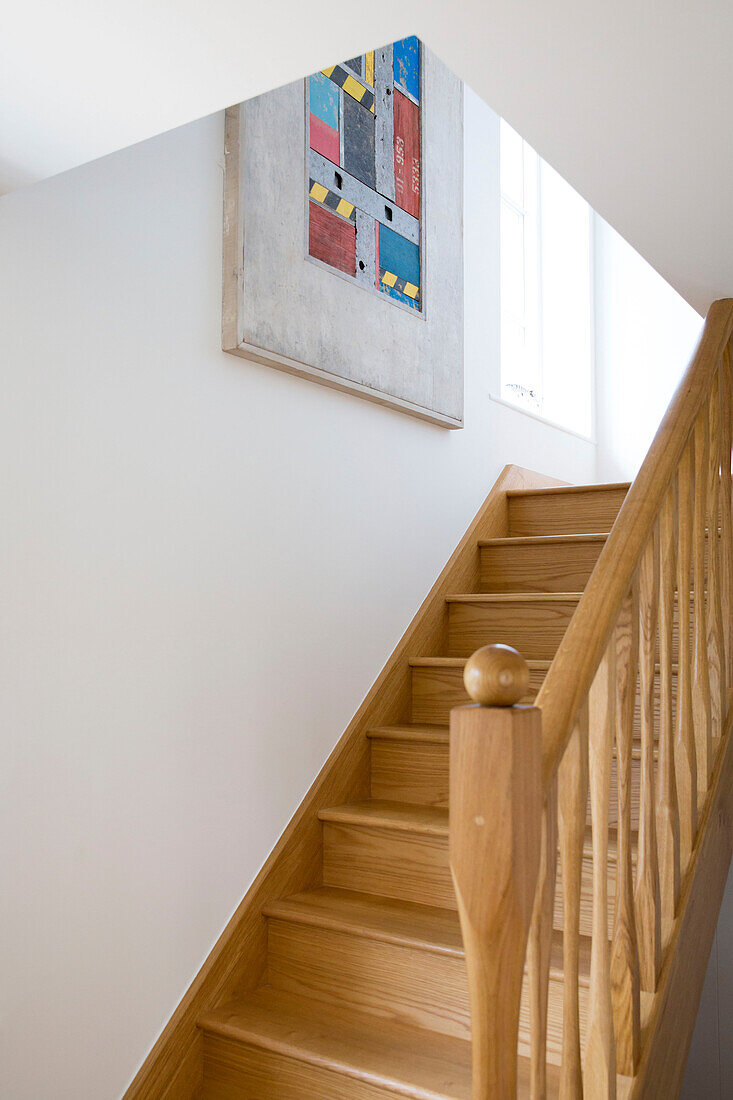 Holztreppe und Geländer mit Kunstwerken in einem Haus in West Wittering, West Sussex, England