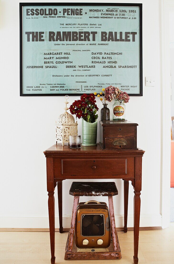 Vintage poster and wooden side table in hallway of London family home,  England,  UK