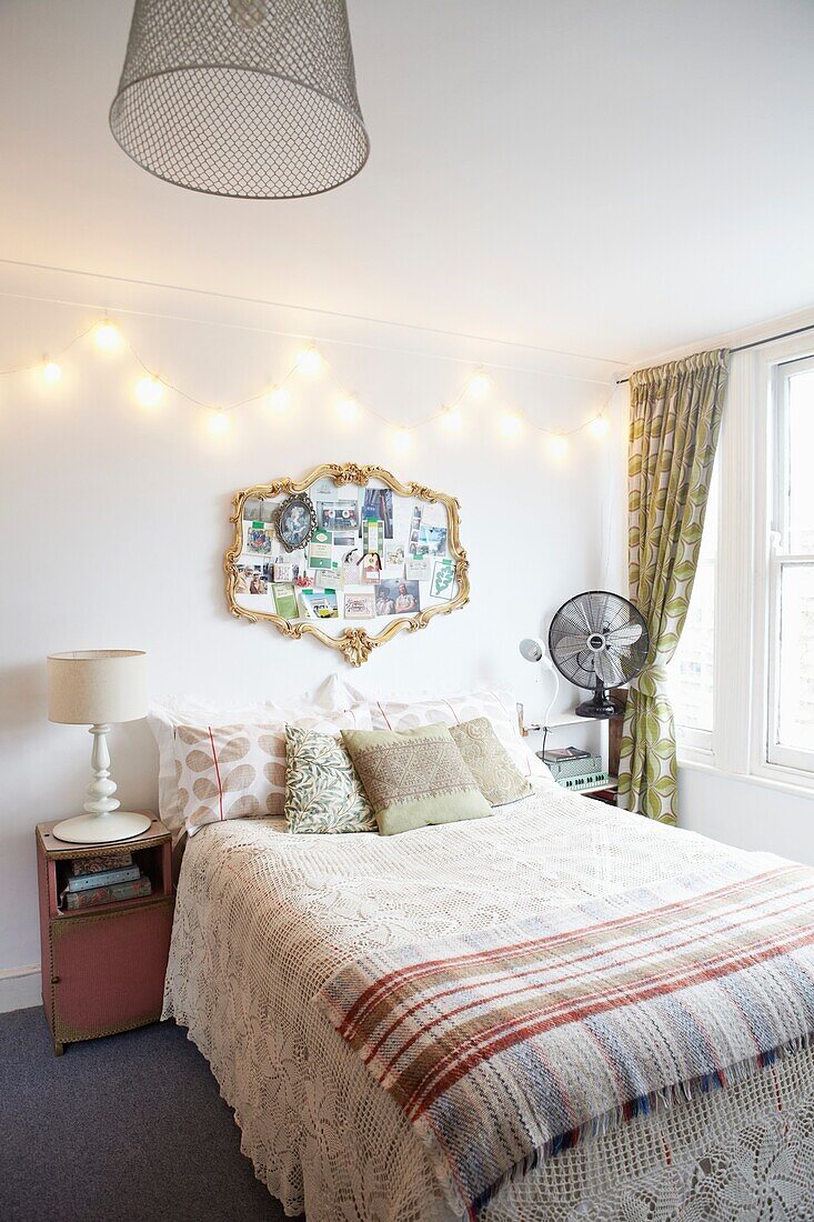 Vergoldeter Vintage-Spiegel über dem Doppelbett mit karierter Decke in der Wohnung einer Londoner Familie, England, UK
