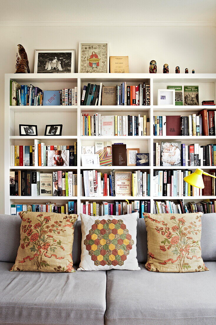 Bücherregal und Sofa mit Polstern in einem Londoner Einfamilienhaus England UK
