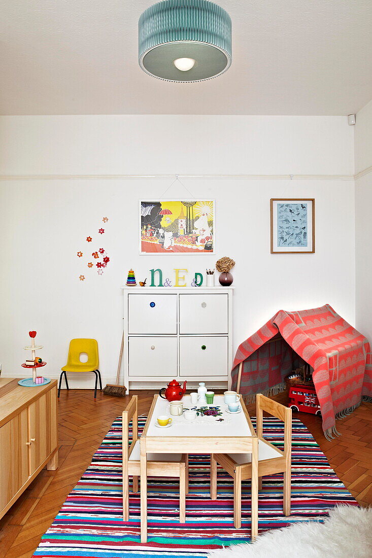 Spielhaus mit Tisch und Stühlen auf gestreiftem Teppich im Kinderzimmer eines Londoner Einfamilienhauses England UK