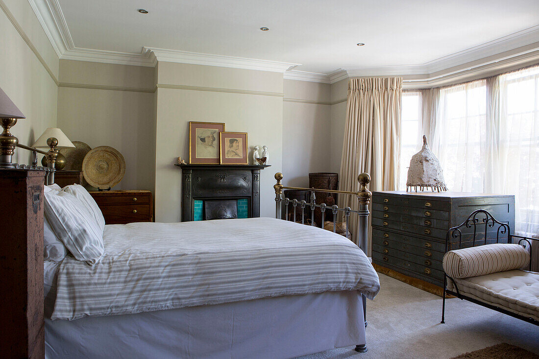 Gestreifte Bettdecke auf Doppelbett mit Vintage-Schubladen und Schlafcouch in edwardianischem Stadthaus in West Sussex England UK