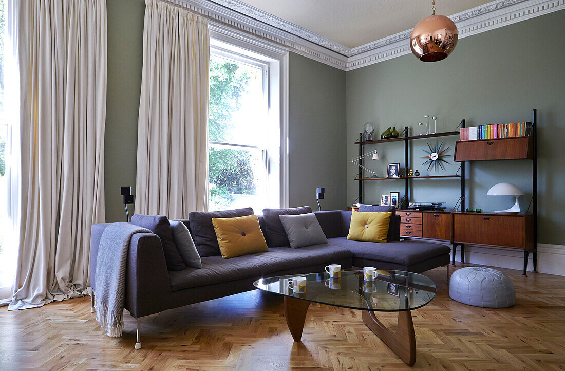 Graues Ecksofa mit gläsernem Couchtisch im Parkett-Wohnzimmer eines Londoner Einfamilienhauses, England, UK