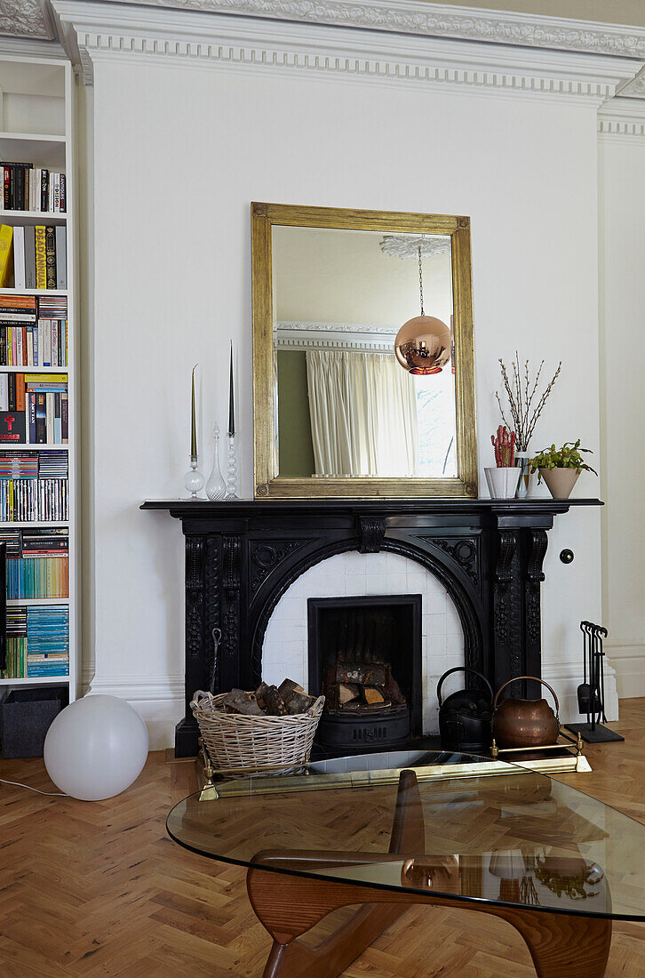 Gilt-framed mirror on black fireplace in London family home,  England,  UK