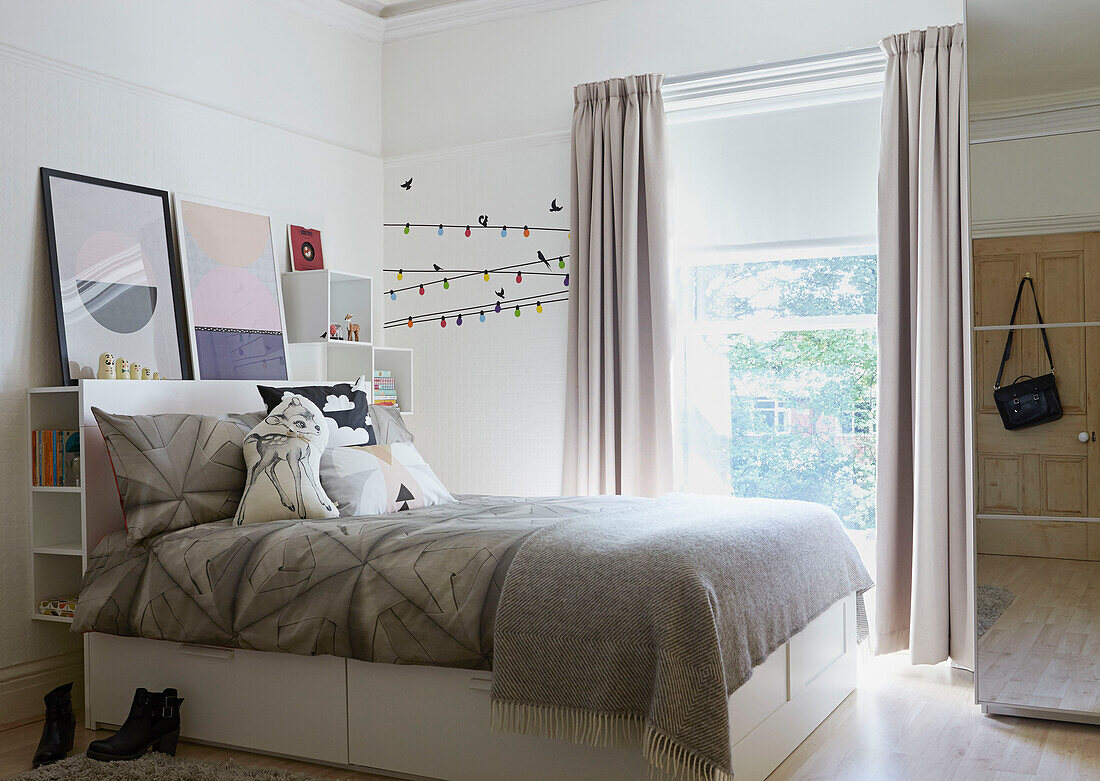 Graue Bettbezüge auf einem Doppelbett am Fenster eines Londoner Einfamilienhauses, England, UK