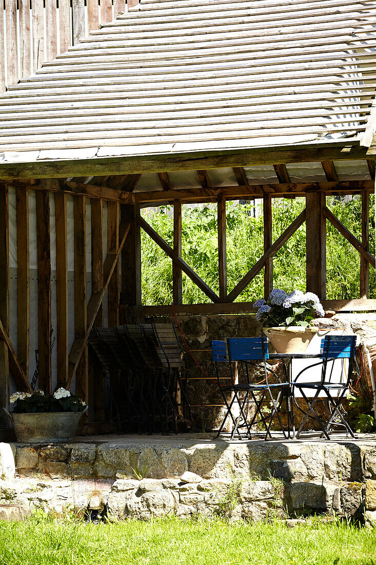 Blue chairs and table in shaded farmhouse exterior in rural United Kingdom