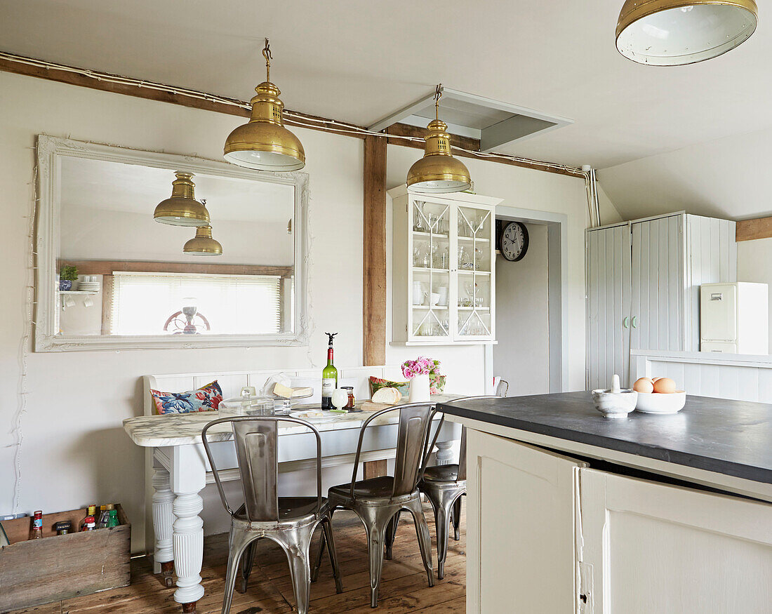 Copper pendant lights above table with mirror in UK farmhouse kitchen