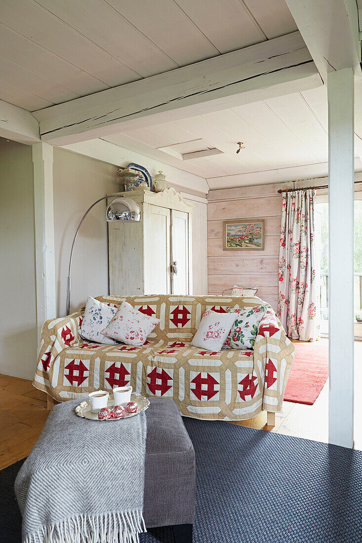 Patterned throw on sofa in open plan living room of UK farmhouse