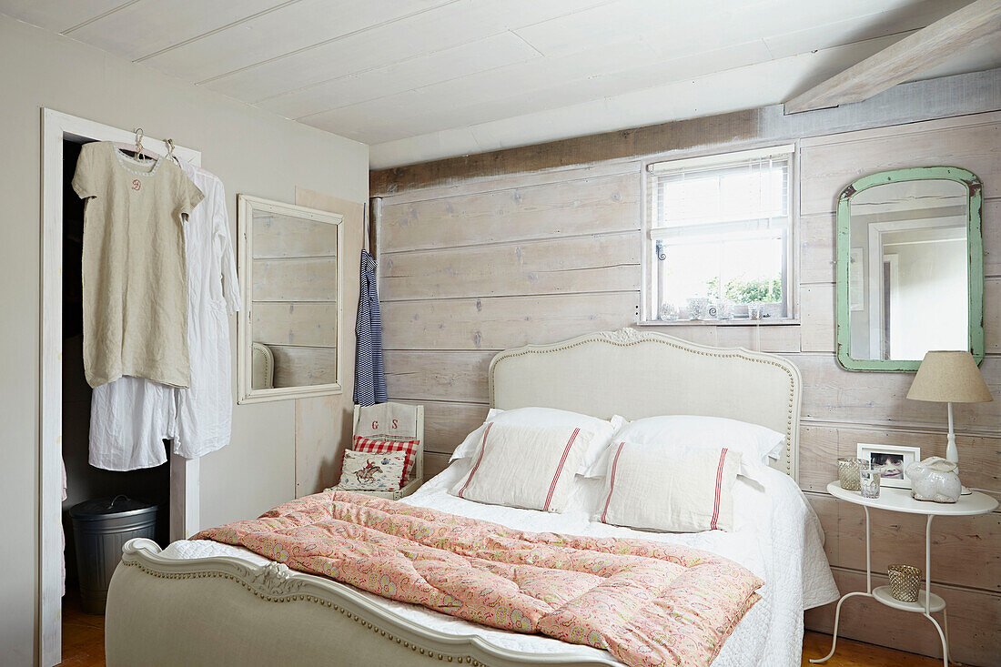 Steppdecke auf Doppelbett mit hellgrünem Spiegel an getäfelter Wand in britischem Bauernhaus-Schlafzimmer