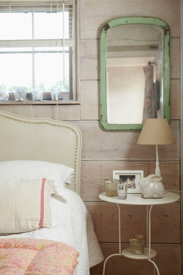 Light green mirror at panelled bedside in UK farmhouse