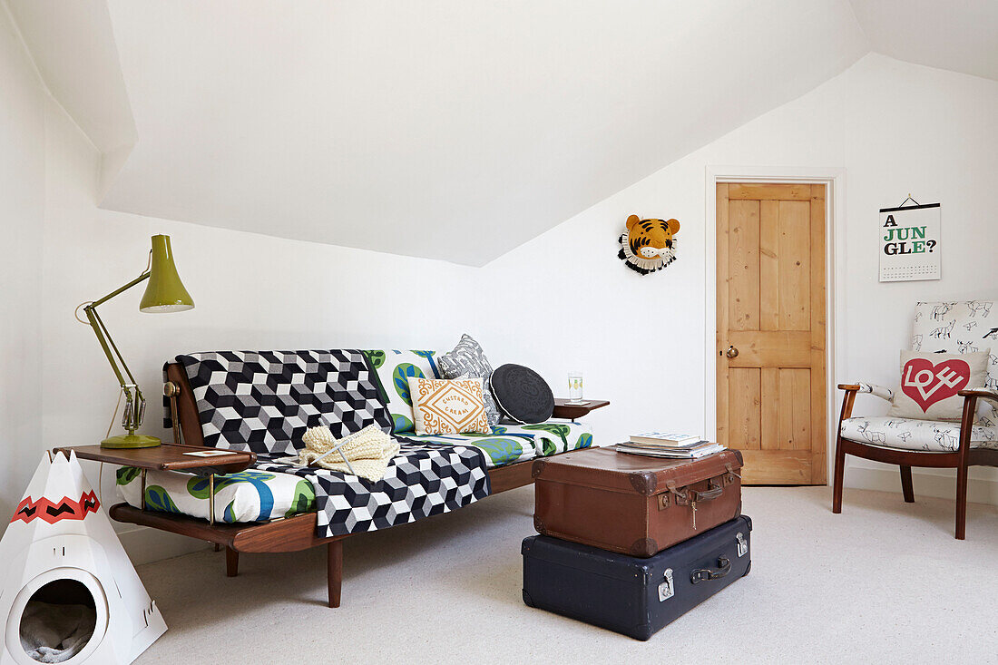 Holzsessel und Sofa mit alten Koffern in einem Londoner Dachgeschoss-Wohnzimmer, England, UK