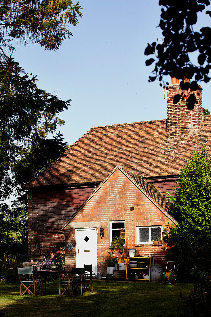 Gartenmöbel und Backsteinfassade des Bauernhauses von Brabourne, Kent, Großbritannien