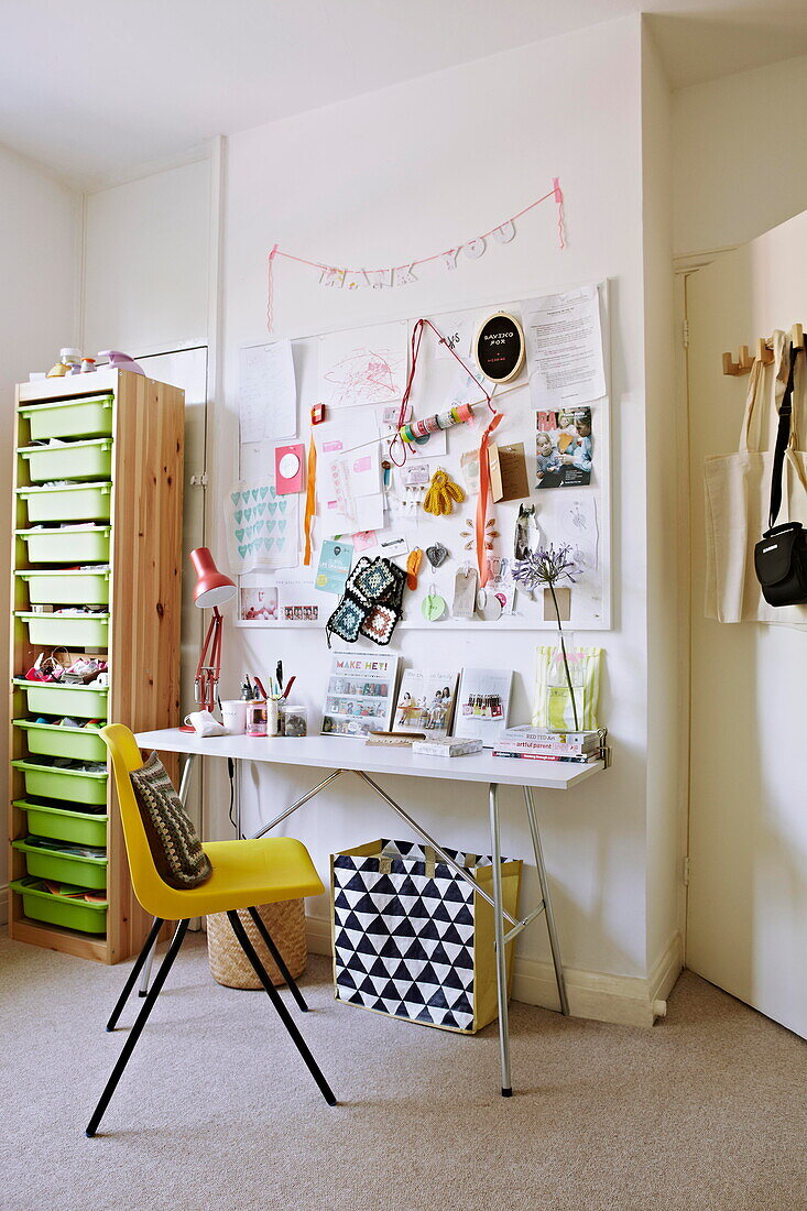 Limonengrüne Schubladen und Pinnwand mit Schreibtisch im Arbeitszimmer einer Künstlerin in einem Londoner Einfamilienhaus England UK