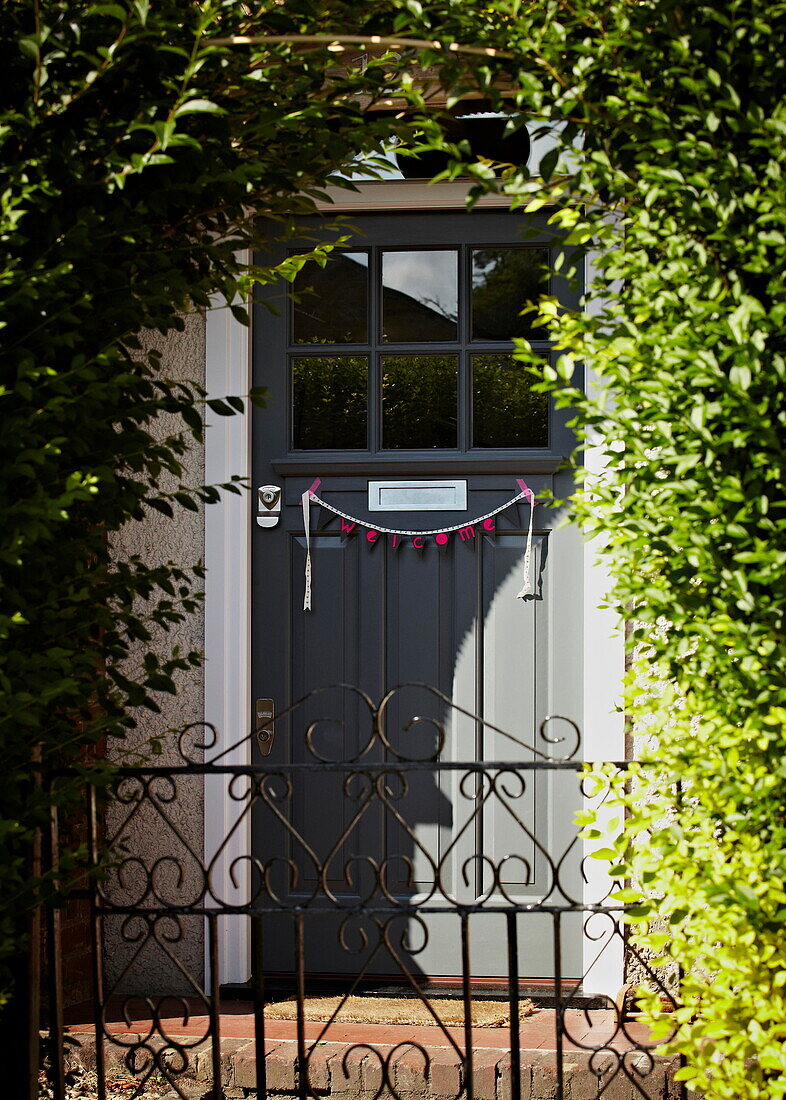 Grey front door with bunting and wrought iron gate  exterior of London family home  England  UK