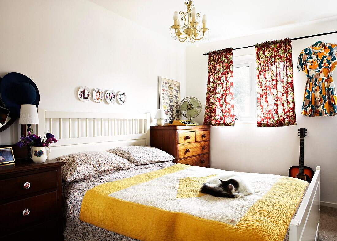 Cat sleeping on yellow quilt in retro style bedroom of Birmingham home