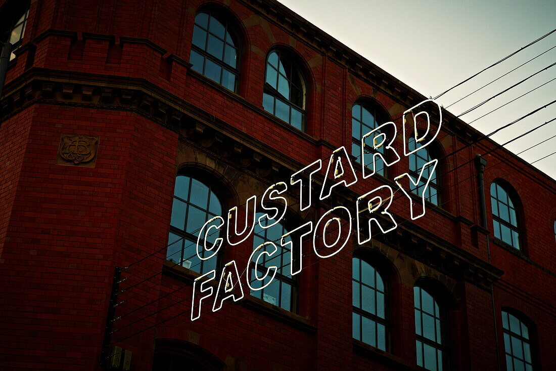 Großer Schriftzug 'CUSTARD FACTORY' in Neonlichtern vor einem Wohnhaus Birmingham UK