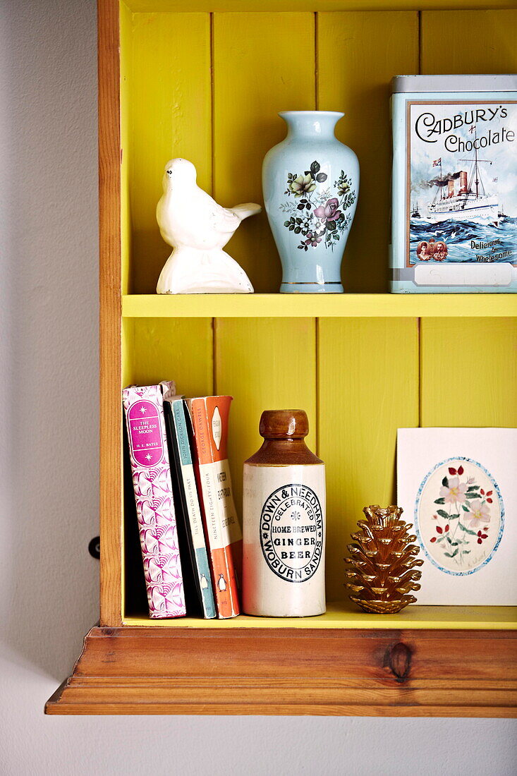 Ornamente und Bücher in einem Wandregal in einer Wohnung in Birmingham, England UK