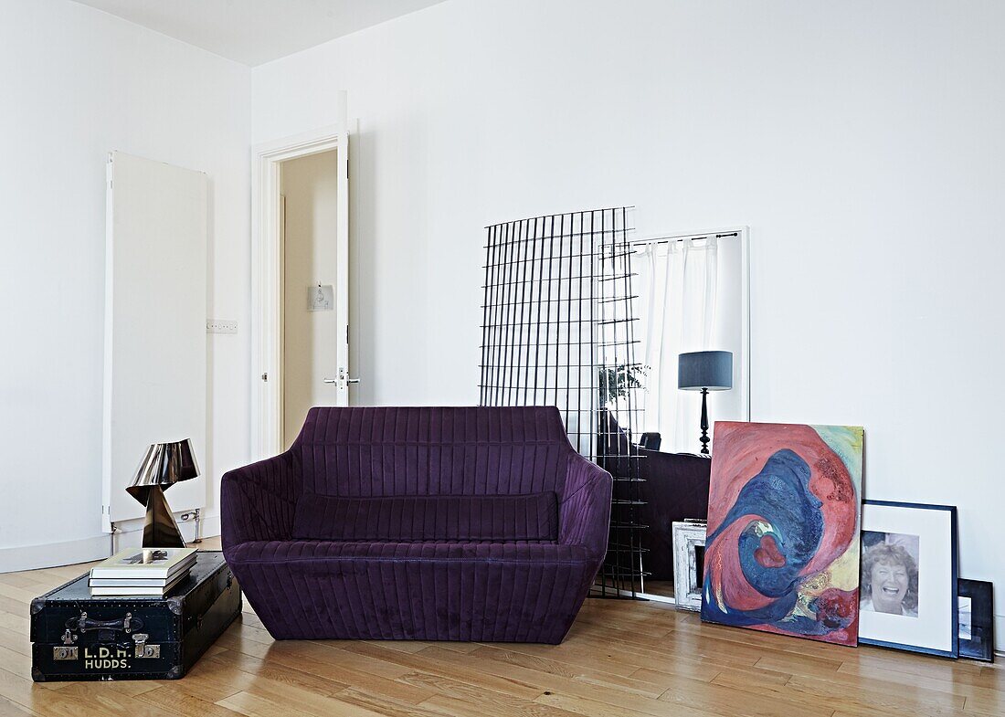 Lila Zweisitzer-Sofa mit Vintage-Koffer im Wohnzimmer eines modernen Londoner Einfamilienhauses England UK
