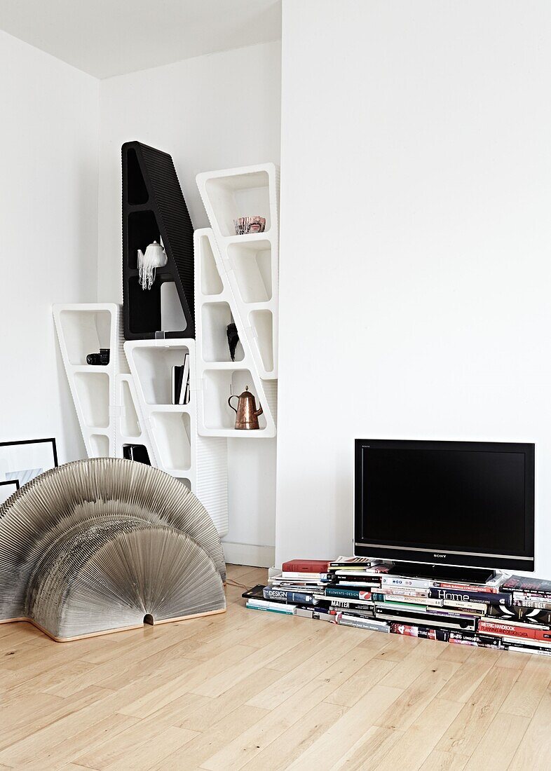 TV und Bücher mit wandmontiertem Regal im Wohnzimmer einer modernen Londoner Wohnung England UK