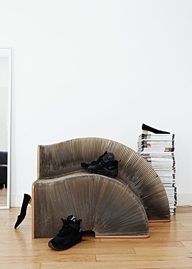 Zeitschriftenstapel mit Sportschuhen auf einem skulpturalen Regal in einer modernen Londoner Wohnung England UK