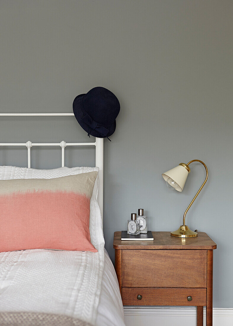 Hut auf weißem Kopfteil mit hölzernem Nachttisch in modernem Londoner Haus England UK