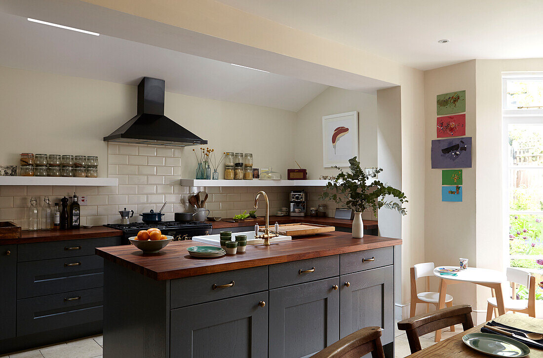 Dunkelgraue Küchenschränke mit Holzarbeitsplatten und weißen Kacheln in einem modernen Londoner Einfamilienhaus England UK