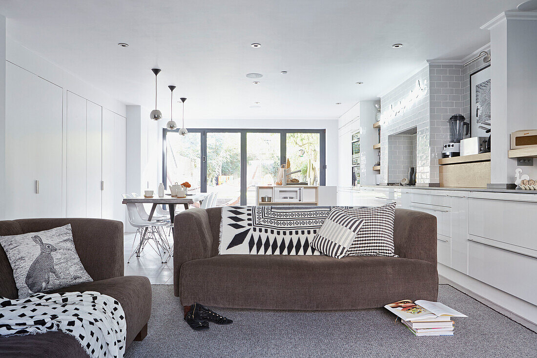 Braune Sofas mit schwarzen und weißen Kissen in einem offenen Londoner Stadthaus England UK