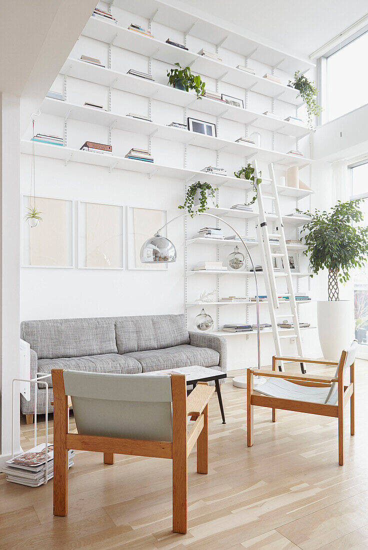 Sesselpaar in einem Wohnzimmer mit doppelter Höhe und vom Boden bis zur Decke reichenden Regalen in einem Londoner Haus UK