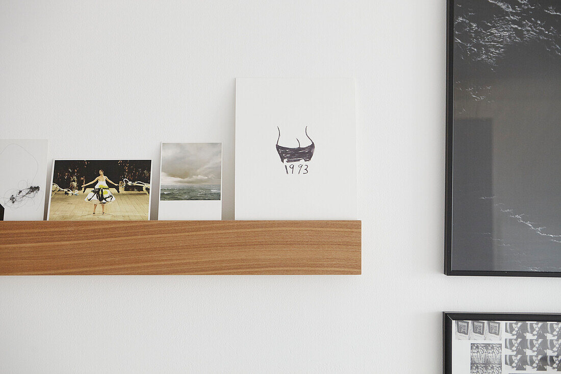 Verschiedene Postkarten auf einem Regal mit gerahmten Kunstwerken in einer Londoner Wohnung UK