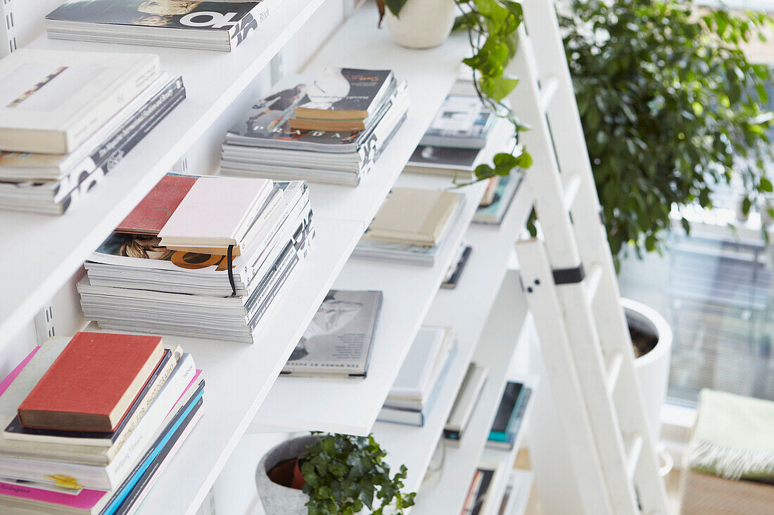 Stacked magazines ordered onto open shelving in London apartment  UK