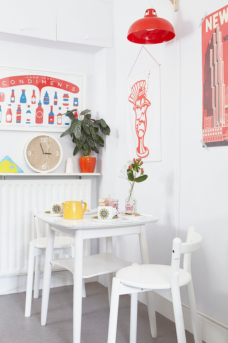 Weißer Tisch und Stühle mit roter Pendelleuchte und Kunstwerk in der Küche von Alloa, Schottland UK