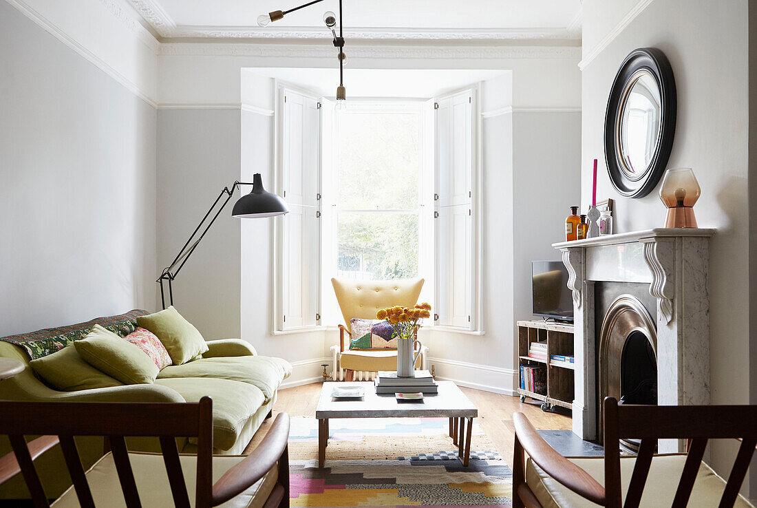 Runder Spiegel über Marmorkamin mit Vintage-Möbeln in einem Londoner Haus UK