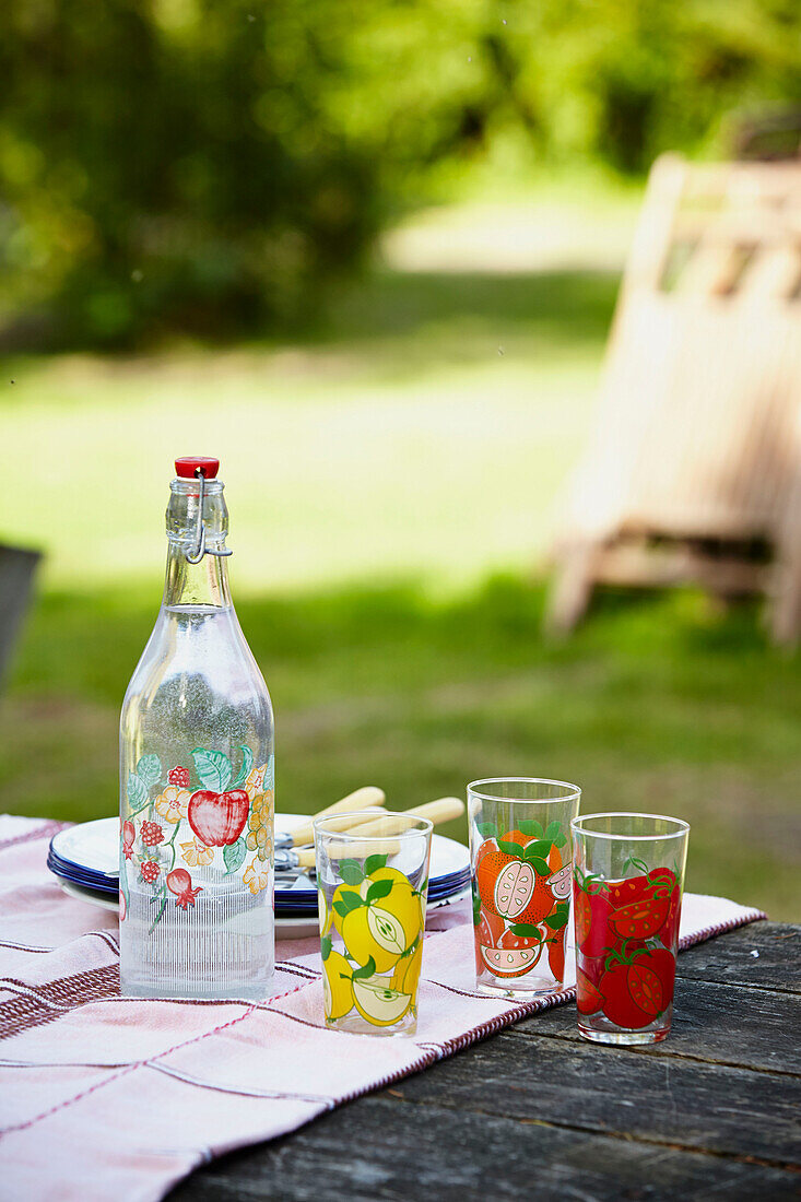 Flasche und Teller auf einem Picknicktisch im Garten von Brabourne, Kent, Großbritannien