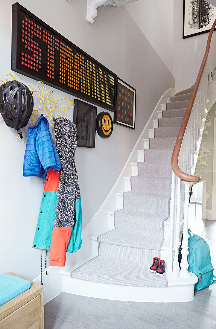 Cycling helmet and coats with pop art in staircase hallway of London townhouse  England  UK