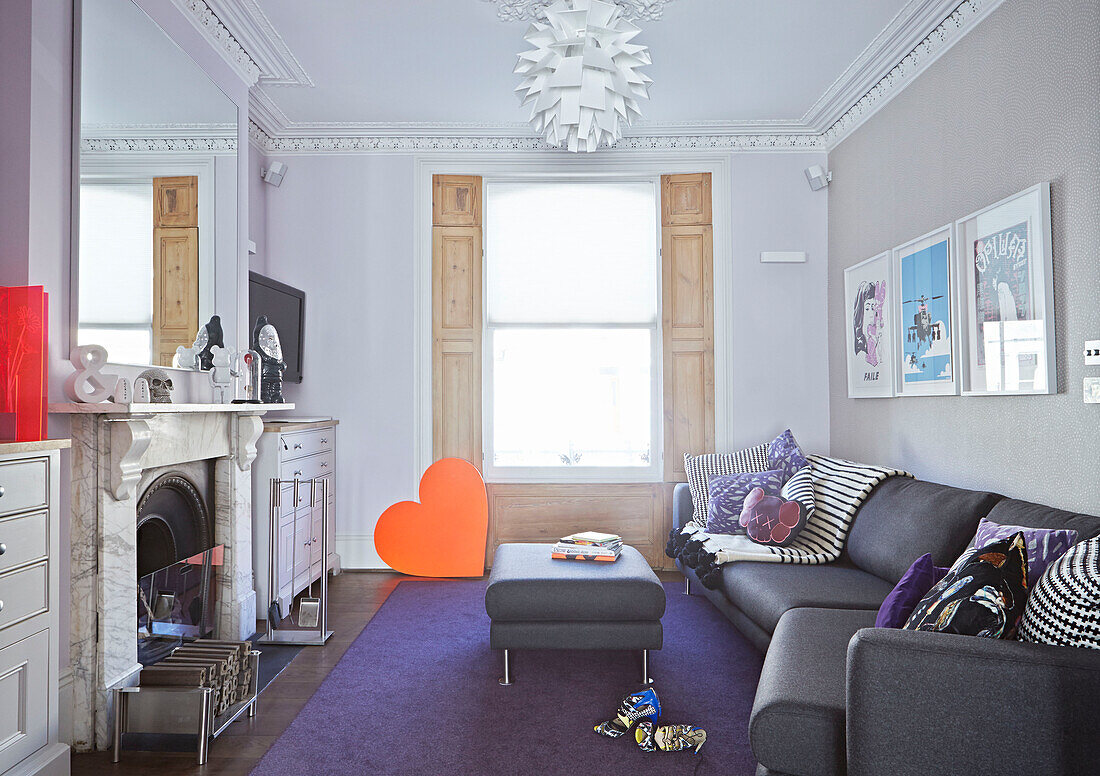 Graues Sofa und Ottomane mit orangefarbenem Liebeskranz im Wohnzimmer eines Londoner Stadthauses England UK