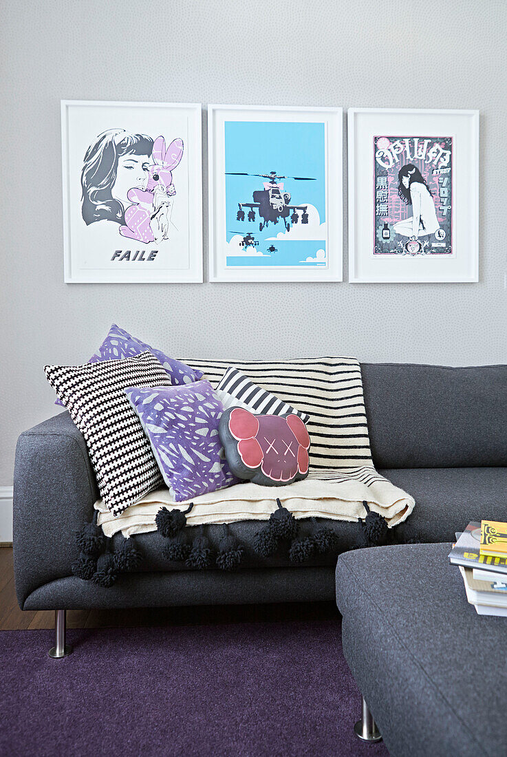 Framed prints above sofa with cushions in living room of London townhouse  England  UK