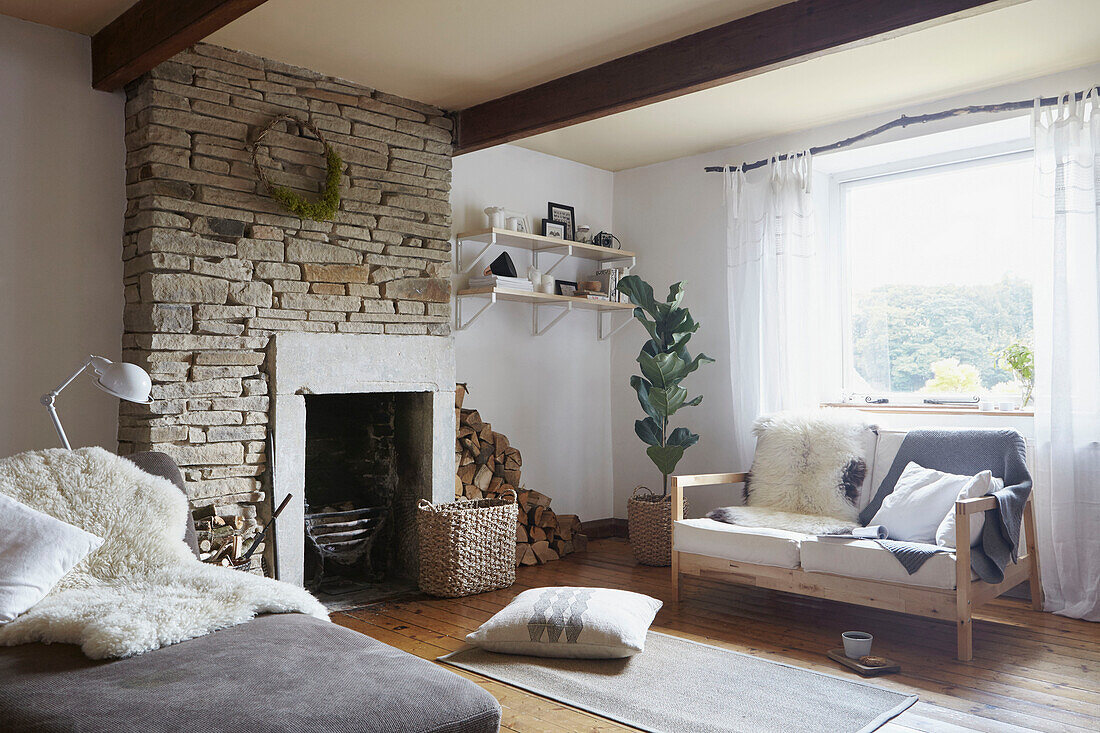 Freigelegte Steinschornsteinbrust und Sitzgelegenheit mit Feuerholz in einem Wohnzimmer in West Yorkshire UK
