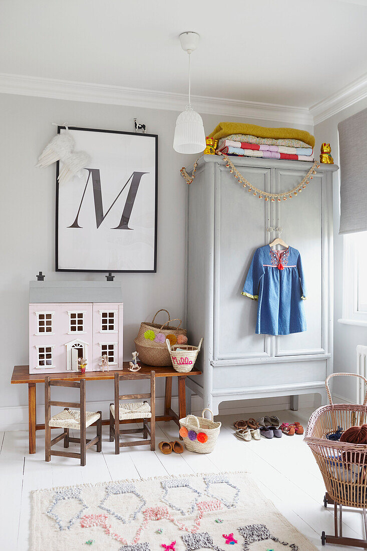 "Gefaltete Decken auf Kleiderschrank mit gerahmtem Buchstaben M"" und Puppenhaus im Schlafzimmer einer Londoner Familie UK"""