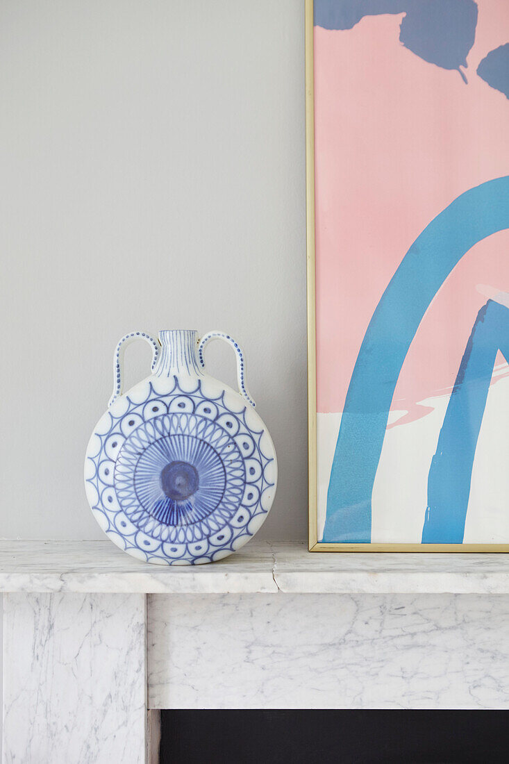 Blue and white ceramic flask with modern artwork on mantlepiece in London home  UK
