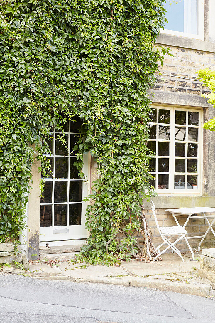 Overgrown doorway and windows on stone facade of West Yorkshire home  UK