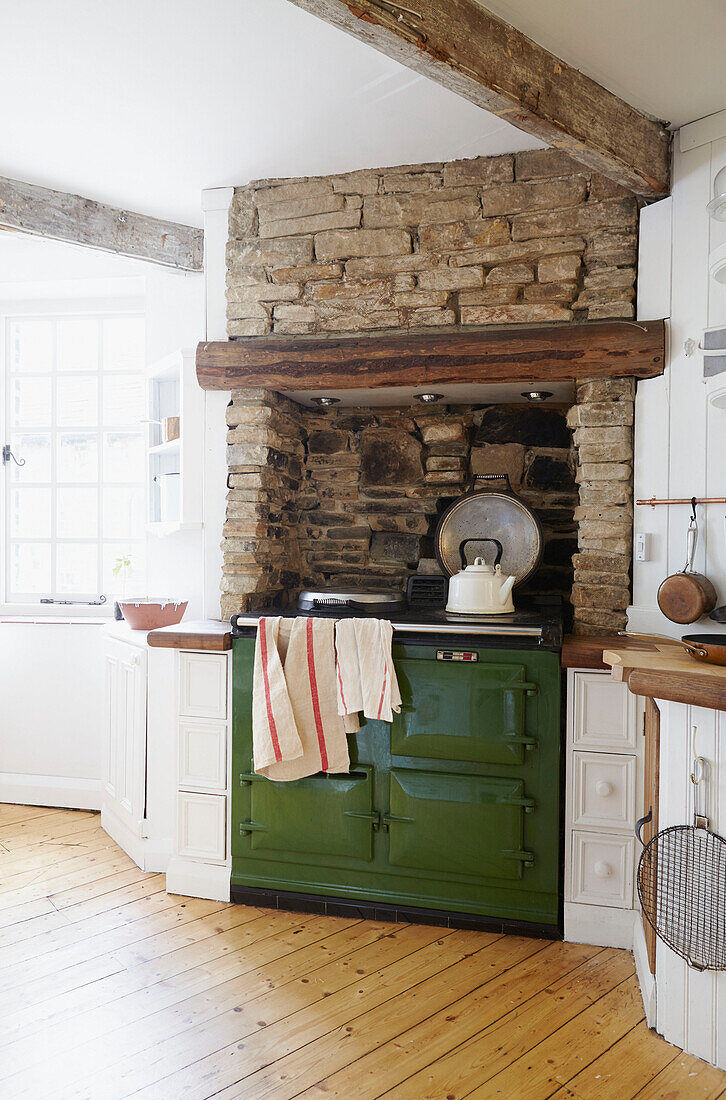 Green range oven with exposed stone wall in farmhouse kitchen  West Yorkshire  UK