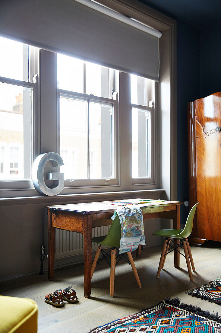Desk and chairs at sash windows with letter 'G' in East London townhouse  England  UK