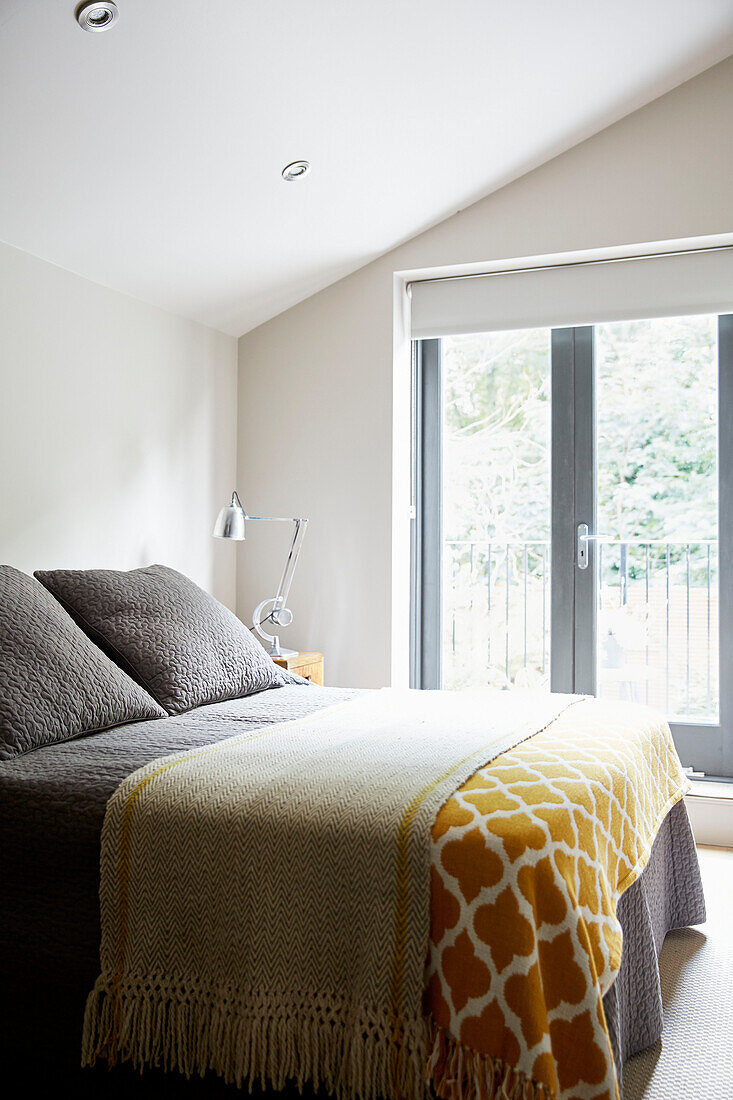 Graues Doppelbett mit senfgelben Decken in einem Stadthaus in East London England UK