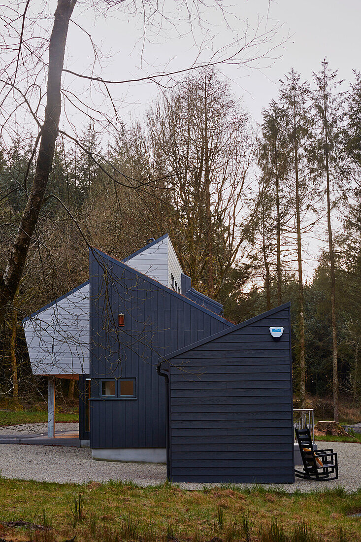 Graue holzverkleidete Fassade eines Neubaus in einem Waldgebiet in Devon, Großbritannien