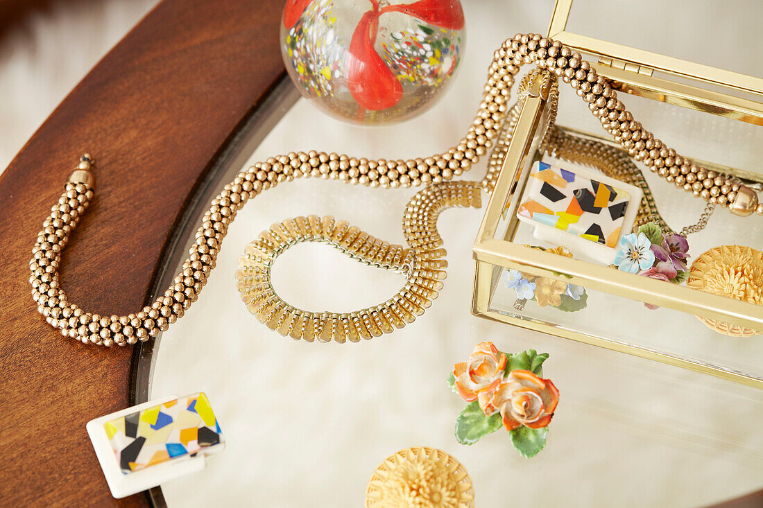 Gold necklaces with glass jewellery box on tabletop in London home  UK