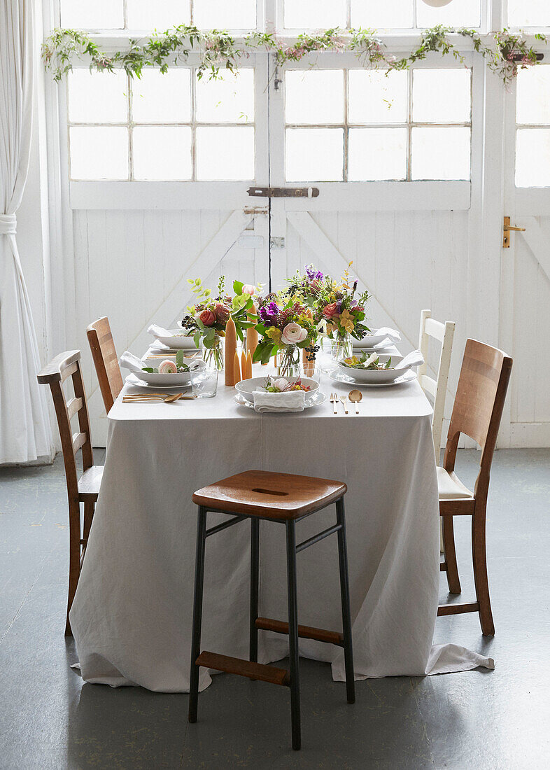 Gedeckter Esstisch mit langer Tischdecke und Blumen in einem Londoner Haus UK