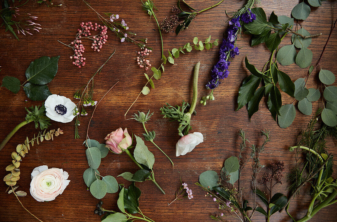 Verschiedene Blumenköpfe und Laub auf einem Holztisch in einem Londoner Haus UK