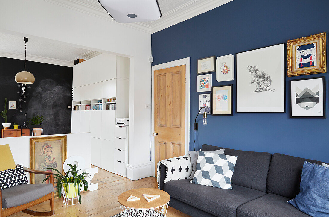 Gerahmtes Kunstwerk an blauer Wand über dem Sofa im Arbeitszimmer eines modernisierten Hauses in Preston, Lancashire, England, UK